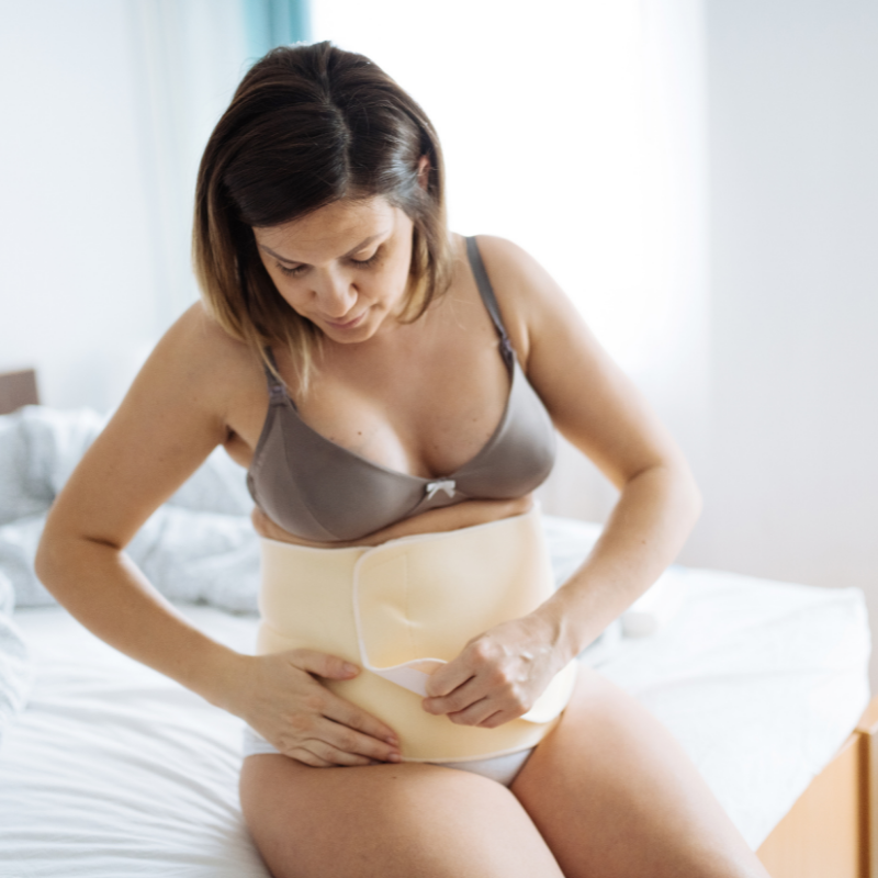 woman sitting on bed putting a belly band on