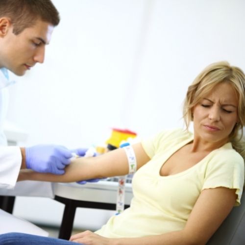 woman looking away as male does a blood draw 