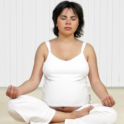 pregnant person sitting with legs crossed meditating