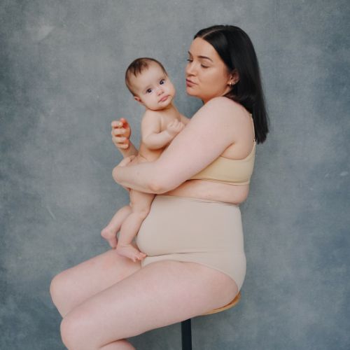 mom holding a baby wearing postpartum compression garment