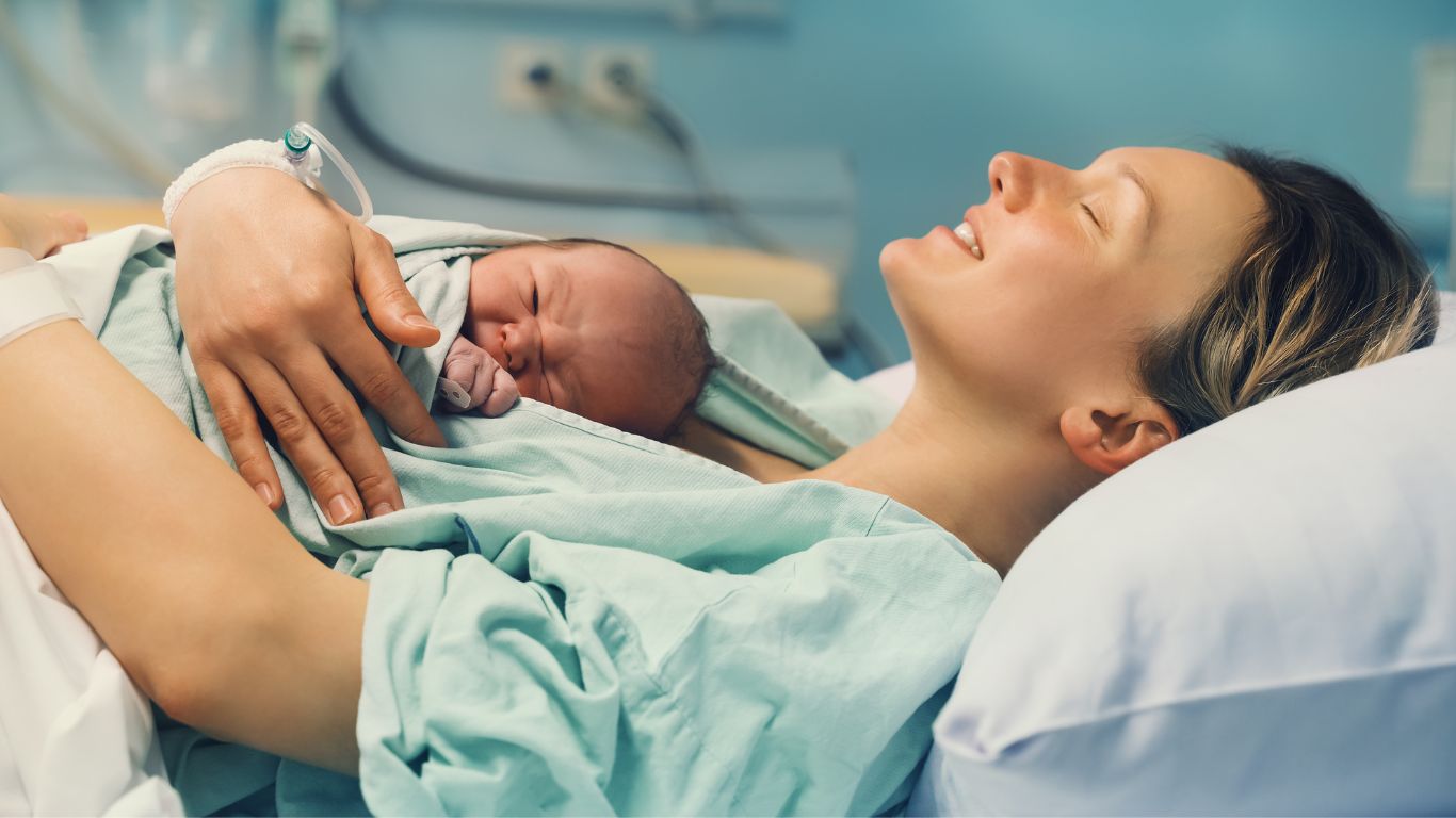 mom in hospital gown holding baby after birth