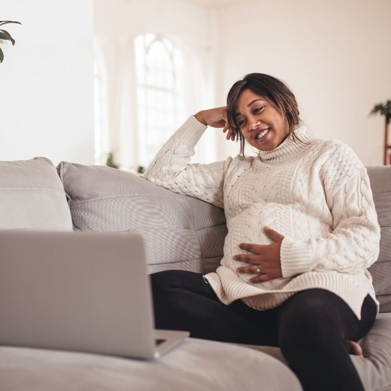 pregnant person on couch with computer